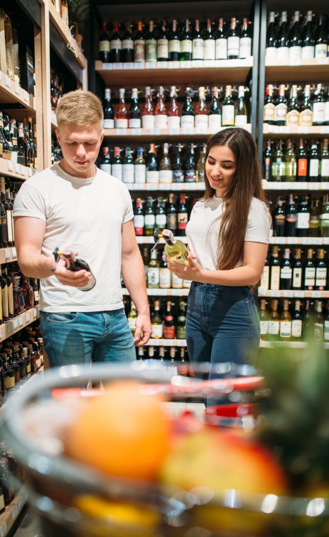 Young couple looking for wine in alcohol market